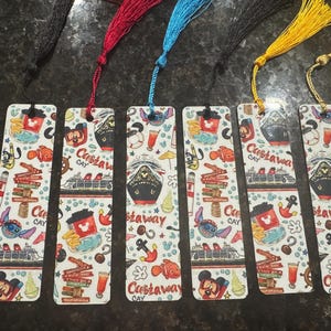 May include: Six rectangular bookmarks with colorful illustrations and tassels. Each bookmark features a cruise ship, Mickey Mouse, Stitch, and the words "Castaway Cay". The tassels are black, red, blue, yellow, and gold.