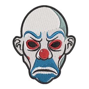 Puede incluir: Un parche bordado que muestra un rostro de payaso estilizado con piel blanca, cejas azules, cuencas oculares rojas, nariz roja y una forma triangular azul que cubre la zona de la boca y la barbilla. El diseño tiene un borde negro grueso.