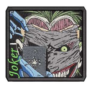 Puede incluir: Un parche bordado cuadrado que muestra a un personaje con cabello verde y una máscara gris sobre el rostro. El personaje sostiene un teléfono inteligente gris oscuro con un icono de bufón. La palabra Joker está bordada en verde brillante a la izquierda.