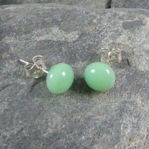 May include: A pair of silver stud earrings with light green round gemstones.