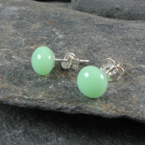 May include: A pair of silver stud earrings with light green round gemstones.