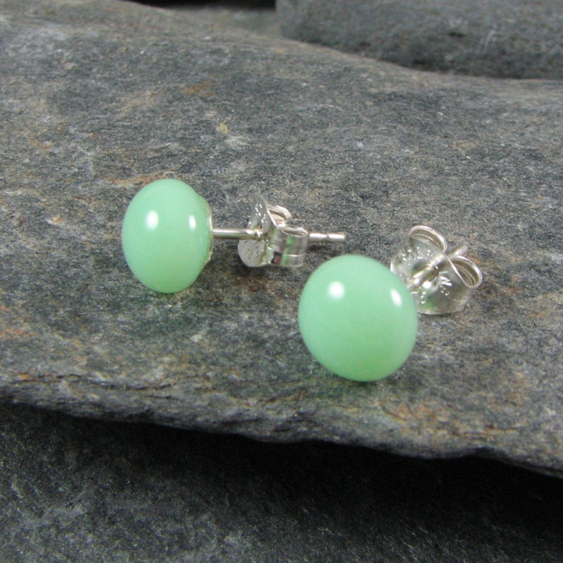 May include: A pair of silver stud earrings with light green round gemstones.