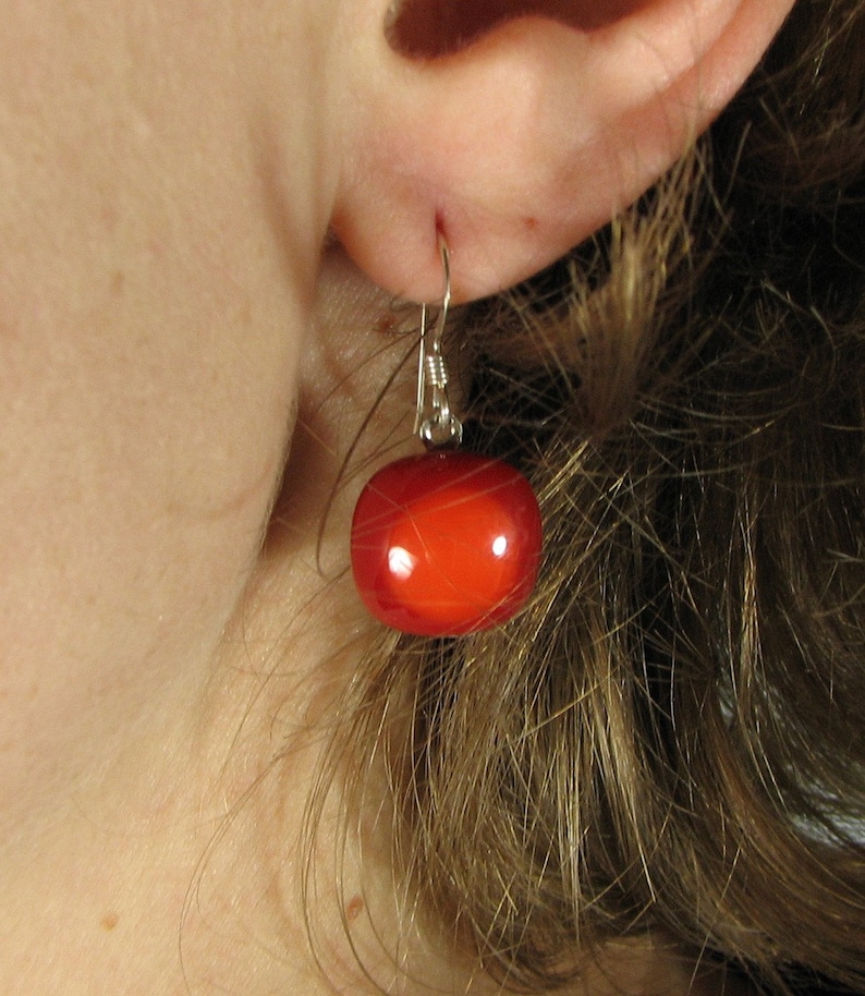 May include: A pair of silver earrings with a single red bead on each earring.