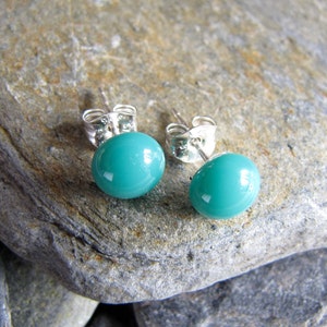 May include: A pair of silver stud earrings with turquoise blue round glass stones.