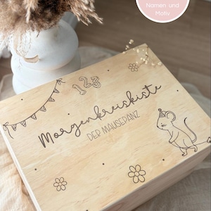 Könnte beinhalten: Eine rechteckige Holzkiste in heller Farbe mit lasergravierten Motiven, darunter der Text 123, Morgenkreiskiste und DER MAUSEPANZ, sowie Abbildungen einer Wimpelkette, Blumen und einer Maus mit einem Partyhut.