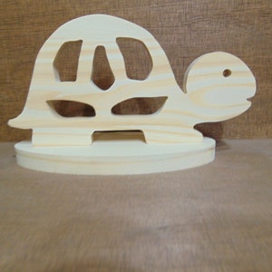 May include: A wooden turtle figurine with a cutout design. The turtle is standing on a small wooden base.
