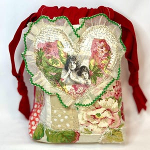 May include: A patchwork fabric drawstring bag with a red velvet top and ties. The bag features a heart-shaped appliqué with a vintage image of two children, surrounded by floral and patterned fabric patches.