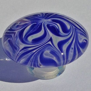 Puede incluir: Un hongo de vidrio azul y blanco con un patrón de remolino. El hongo está hecho de vidrio y tiene una base transparente.