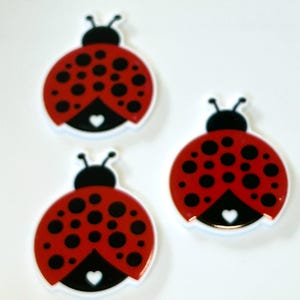 May include: Three red and black ladybug-shaped buttons with white hearts on their undersides.