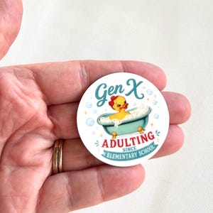 May include: A circular sticker featuring a yellow rubber duck in a teal bathtub filled with bubbles. The text reads Gen X ADULTING SINCE ELEMENTARY SCHOOL in teal and red lettering, surrounded by small blue bubbles and star accents.