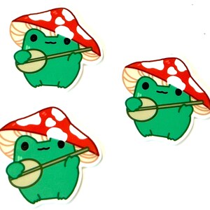May include: Three cartoon frog stickers with red and white mushroom hats playing banjos. The frogs are green and have black eyes.