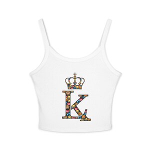 May include: White crop top with thin straps. The top features a large letter "K" and a crown, both decorated with colorful emoji patterns. The design is centered on the front of the top.