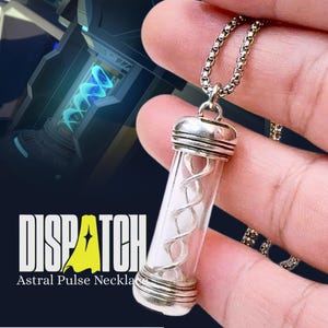 May include: A silver-toned Astral Pulse necklace with a clear, cylindrical pendant. Inside the pendant is a white, spiraling design. The necklace is suspended from a chain. The word "DISPATCH" is displayed with the text "Astral Pulse Necklace".