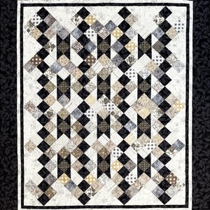 May include: A quilt with a black and white diamond pattern. The diamonds are filled with various patterns in shades of brown, beige, and gray. The quilt is framed with a black border.