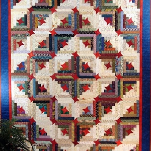 May include: A red, white, and blue quilt with a log cabin pattern and red stars. The quilt is made of many different fabrics and colors.