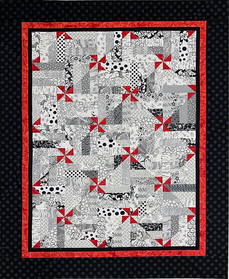 Puede incluir: Una colcha en blanco y negro con detalles de molinetes rojos. La colcha est&aacute; hecha de varias telas con diferentes patrones, incluyendo lunares, rayas y remolinos. La colcha est&aacute; enmarcada con un borde de lunares blancos y negros.