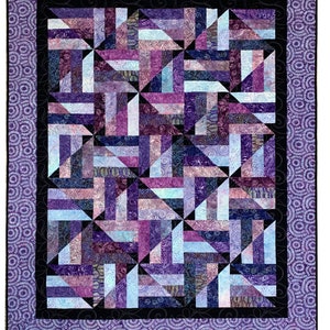 Puede incluir: Una colcha de color morado, azul y blanco con un patr&oacute;n geom&eacute;trico. La colcha est&aacute; enmarcada con un borde morado.