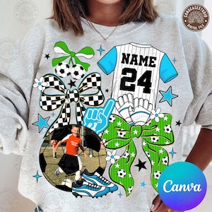May include: A gray sweatshirt with a soccer-themed design. The design includes a soccer jersey with the name and number 24, soccer balls, bows, stars, soccer cleats, and a photo of a child playing soccer. The word "Canva" is also visible.