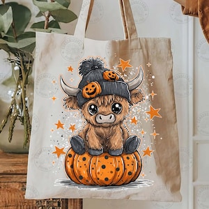 May include: A beige tote bag featuring a cartoon illustration of a Highland cow wearing a gray beanie with pumpkin accents, sitting on an orange pumpkin. Orange stars and sparkles surround the cow, creating a festive Halloween theme.
