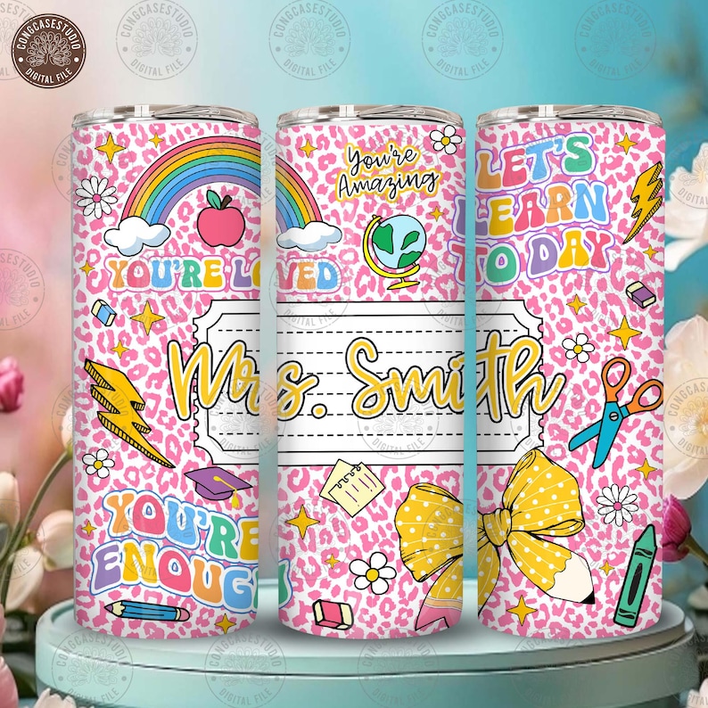 Peut inclure: Un gobelet rose avec un motif l&eacute;opard et des graphiques sur le th&egrave;me de l'&eacute;cole. Le gobelet pr&eacute;sente un arc-en-ciel, une pomme et le texte "You're Loved", "You're Amazing" et "Let's Learn Today". Il y a aussi une &eacute;tiquette nominative qui dit "Mrs. Smith".