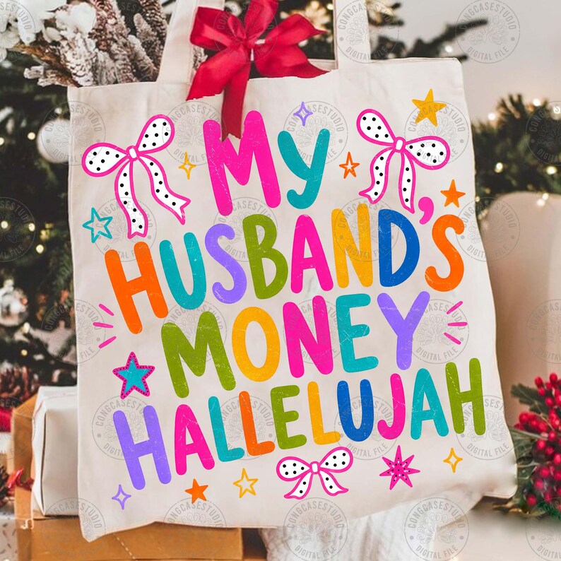 K&ouml;nnte beinhalten: Eine cremefarbene Canvas-Tragetasche mit einer gro&szlig;en roten Stoffschleife oben. Die Tasche zeigt den bunten Schriftzug "MY HUSBAND'S MONEY HALLELUJAH" in einer verspielten Schriftart, akzentuiert durch verschiedene kleine Sterne und drei wei&szlig;e Schleifen mit schwarzen Punkten.