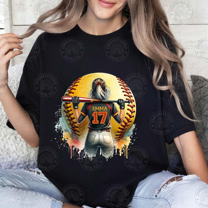 Peut inclure: T-shirt noir avec un motif aquarelle d'une joueuse de softball avec le nom "Emma" et le num&eacute;ro "17" au dos de son maillot.