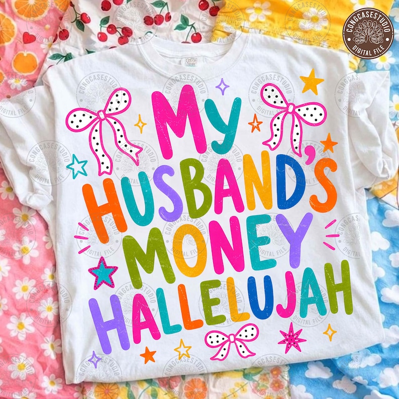 K&ouml;nnte beinhalten: Ein wei&szlig;es T-Shirt mit dem bunten Schriftzug My Husband's Money Hallelujah in Pink, T&uuml;rkis, Orange, Gr&uuml;n und Lila. Das Design ist mit wei&szlig;-schwarzen gepunkteten Schleifen und verschiedenen kleinen gelben, orangen und t&uuml;rkisen Sternen verziert.