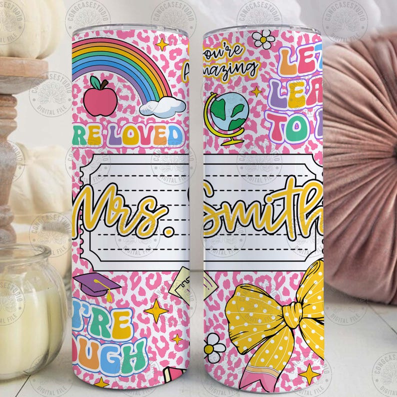 Peut inclure: Un gobelet rose avec un motif l&eacute;opard, avec un arc-en-ciel, une pomme et les mots "RE LOVED". Le gobelet comprend &eacute;galement le nom "Mrs. Smith" et les phrases "You're amazing" et "Let Learn To". Un n&oelig;ud jaune est &eacute;galement pr&eacute;sent.
