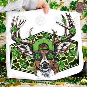 May include: A white graphic featuring a deer wearing a green cap and sunglasses with shamrock lenses. The deer's antlers are adorned with shamrocks, and the background is a green camouflage pattern. The image is a digital file.