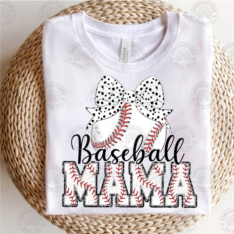 May include: White t-shirt with a black and white polka dot bow on top of a baseball. The text "Baseball Mama" is written in black with red stitching around the letters.