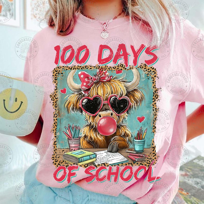 May include: A pink t-shirt with the words "100 Days of School". The design includes a cartoon Highland cow wearing heart-shaped sunglasses and blowing a bubble. School supplies surround the cow.