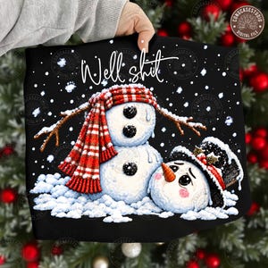 May include: A black t-shirt featuring a graphic of two snowmen with the text "Well shit" above them. One snowman wears a red and white striped scarf, while the other wears a black top hat with holly. White snowflakes are scattered throughout.