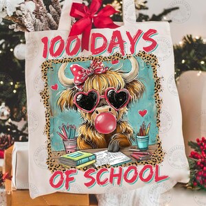 May include: A white tote bag featuring a Highland cow wearing heart-shaped sunglasses and blowing a bubble, with the text "100 DAYS OF SCHOOL" in red. The bag is decorated with a red bow. The design has a leopard print border.