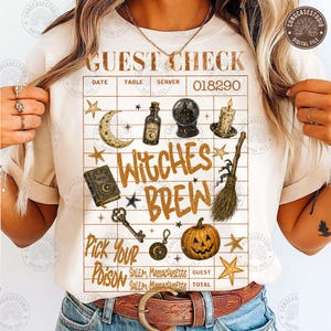 May include: A cream-colored t-shirt featuring a graphic of a guest check with the text GUEST CHECK, WITCHES BREW, and PICK YOUR POISON. The design includes illustrations of a crescent moon, potion bottle, crystal ball, candle, book, broom, and pumpkin.