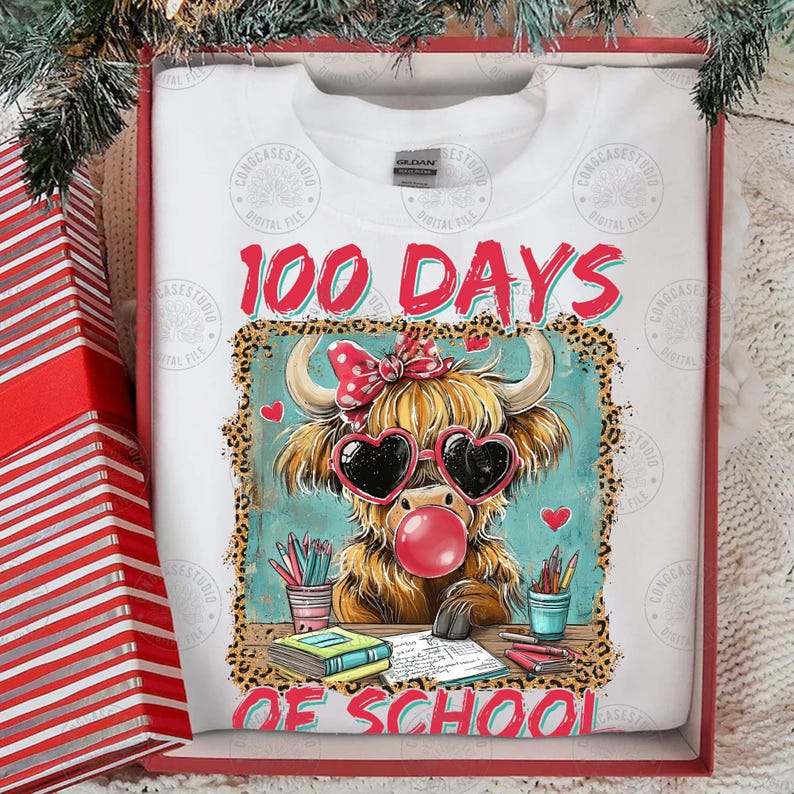 May include: White sweatshirt featuring a Highland cow graphic with heart-shaped sunglasses and a bubble. The text "100 Days of School" is in red. The sweatshirt is in a red gift box. The image is in a red gift box.