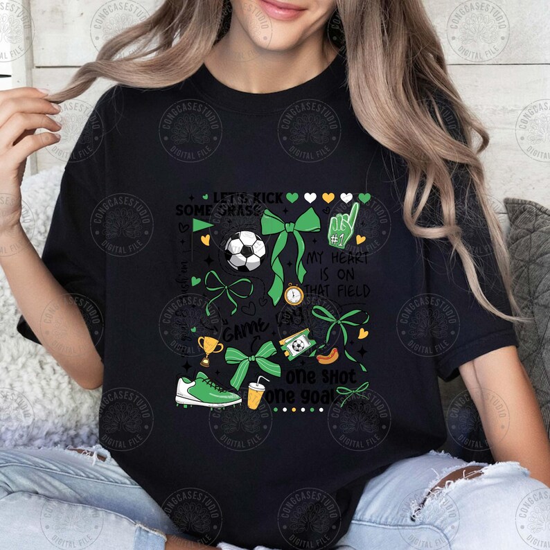 Puede incluir: Camiseta negra con un dise&ntilde;o tem&aacute;tico de f&uacute;tbol. El dise&ntilde;o incluye un bal&oacute;n de f&uacute;tbol, lazos verdes, un trofeo, una bota de f&uacute;tbol y las frases "Let's Kick Some Grass", "My Heart Is On That Field" y "One Shot One Goal".