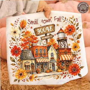 May include: A white fabric square featuring a colorful illustration of a small town street with brick buildings, a water tower, and autumn foliage. The text reads Small town Fall, 90048, and Los Angeles, CA, surrounded by orange and yellow flowers.