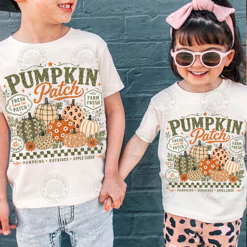 Peut inclure: Deux t-shirts blanc cass&eacute; avec une impression graphique portant le texte PUMPKIN PATCH, FRESH FROM THE PATCH, FARM FRESH, PUMPKINS, HAYRIDES et APPLE CIDER. Le motif comprend diverses citrouilles illustr&eacute;es en orange, vert et beige.