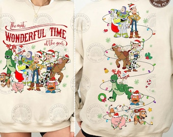 Puede incluir: Sudadera de color crema con un diseño festivo con personajes de una película de animación popular. La parte delantera muestra el texto "The most WONDERFUL TIME of the year" en rojo. La parte trasera muestra los personajes con luces navideñas.