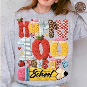 May include: A light gray sweatshirt with a colorful graphic design celebrating 100 days of school. The design includes the words "Happy 100 Days of School" with images of an apple, pencil, and hearts. The text and images are in various textures and patterns.