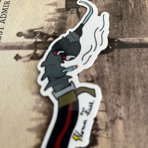May include: A sticker featuring a cartoon illustration of a blowtorch with red eyes and a lit cigarette. The blowtorch is black with a red stripe and the text "Vlown Fuel". The sticker has a white border and a smoke effect.