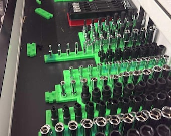 May include: A drawer filled with various sockets and tools, neatly organized on green holders. The sockets are black and silver, arranged in rows. The tools are in a white drawer.