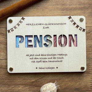 May include: A wooden sign with the word "PENSION" cut out and decorated with money. The sign reads "Herzlichen Gl&uuml;ckwunsch zur Pension" and "Ab jetzt sind deine einzigen Meetings mit dem Kissen und der Couch. Viel Spa&szlig; beim Dauerurlaub! Deine Kollegen."