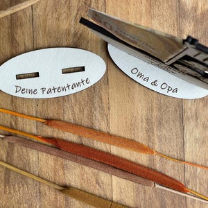 May include: Two wooden signs with slots for money. The sign on the left says "Deine Patentante" and the sign on the right says "Oma & Opa".