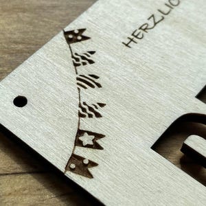May include: A wooden sign with the text "HERZLICH" cut out in the center. The sign is decorated with a string of flags with stars and stripes.