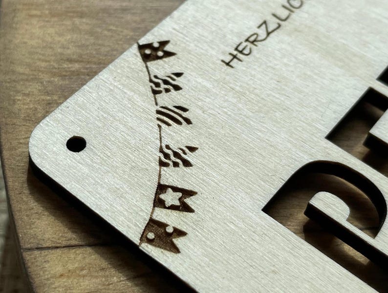 May include: A wooden sign with the text "HERZLICH" cut out in the center. The sign is decorated with a string of flags with stars and stripes.