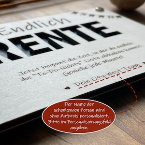May include: A white wooden sign with black lettering that reads "Endlich Rente" and a message about enjoying retirement. The sign is personalized with the text "Dein City-West Team".