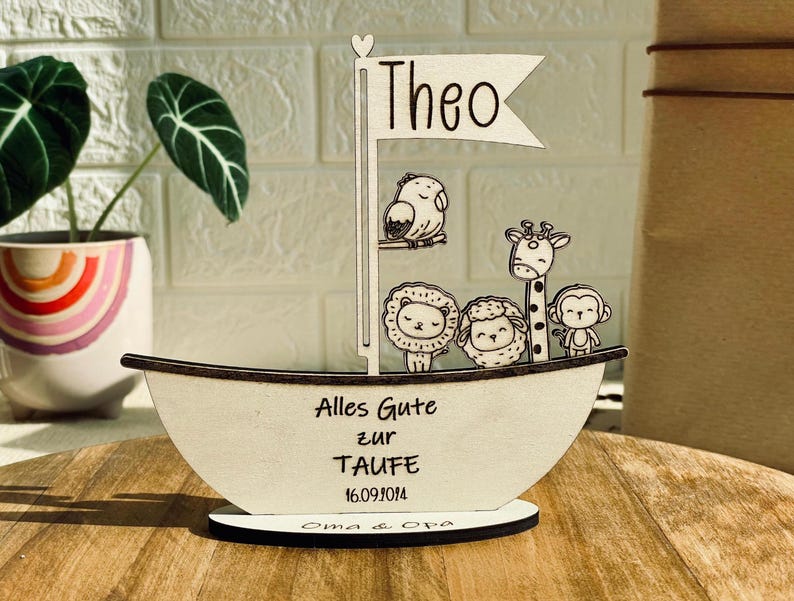 May include: Wooden sailboat shaped sign with the name Theo, animals, and the text "Alles Gute zur Taufe 16.09.1014 Oma & Opa".