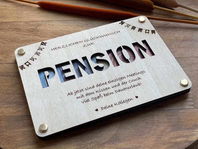 May include: A wooden plaque with the word "PENSION" cut out, surrounded by a string of flags. The plaque has a message that reads "HERZLICHEN GL&Uuml;CKWUNSCH ZUR PENSION Ab jetzt sind deine einzigen Meetings mit dem Kissen und der Couch. viel Spa&szlig; beim Dauerurlaub! Deine Kollegen".