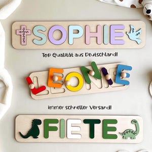 May include: Three rectangular wooden name puzzles featuring pastel, primary, and green-toned letters. The top puzzle spells SOPHIE with a cross and dove. The middle puzzle spells LEONIE with pegs. The bottom puzzle spells FIETE with dinosaur shapes.